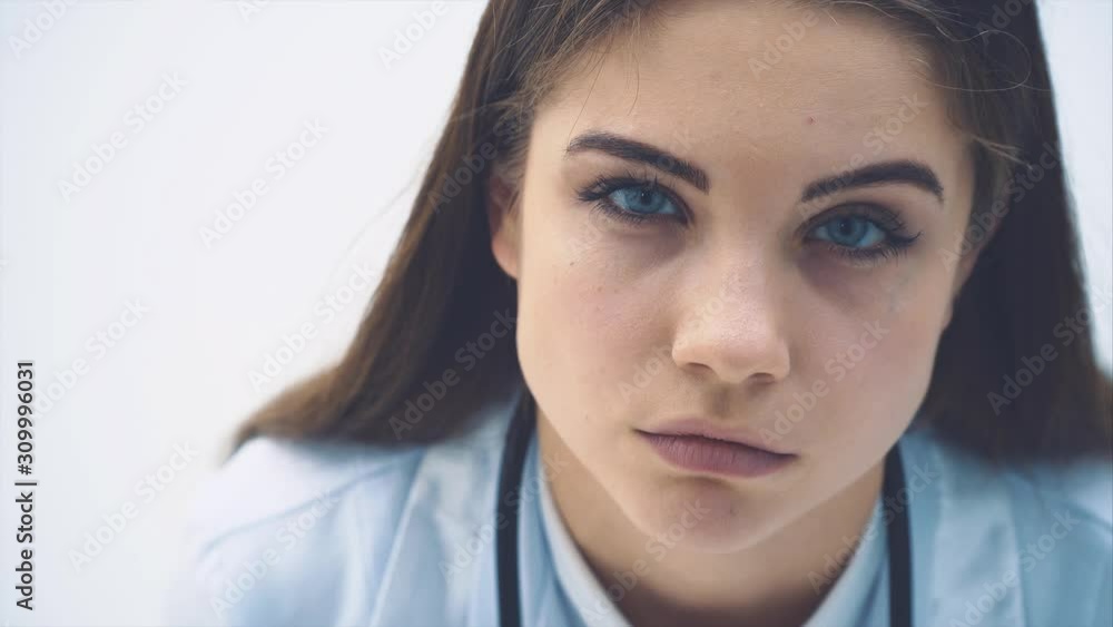 Cute female therapist leaning to the camera, examining it with suspicious and piercing look, raising eyebrows. Long eyelashes, blue eyes. Cute female therapist leaning to the camera, examining it with suspicious and piercing look, raising eyebrows. Long eyelashes, blue eyes.