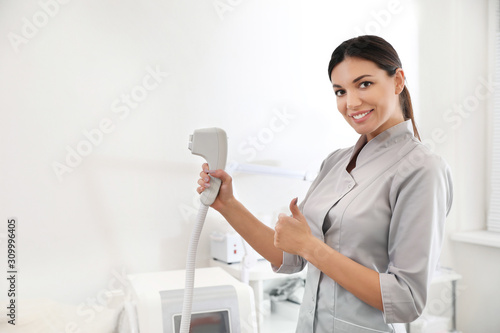 Young woman holding professional laser epilator in beauty salon