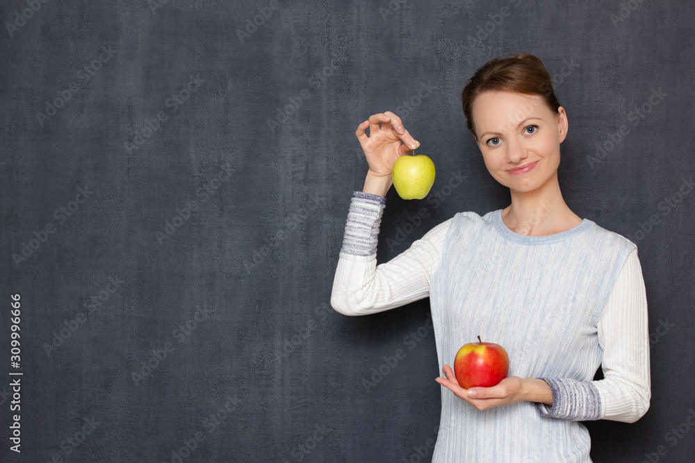 Portrait of happy young woman smiling and holding two ripe apples Portrait of happy young woman smiling and holding two ripe apples
