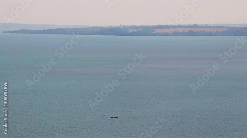 Small fishing boat in the distance moves on open water at Lake Victoria, island in background photo