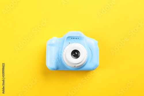 Light blue toy camera on yellow background, top view