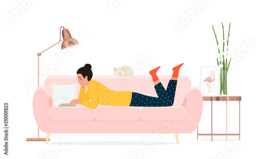A girl reads a book on the couch.