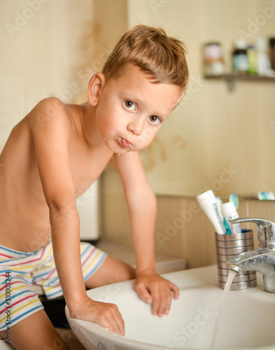 boy rinses his mouth in bathroom over sink