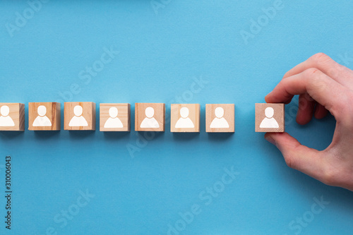 Hand choosing a wooden person block from a set. Employment choice concept