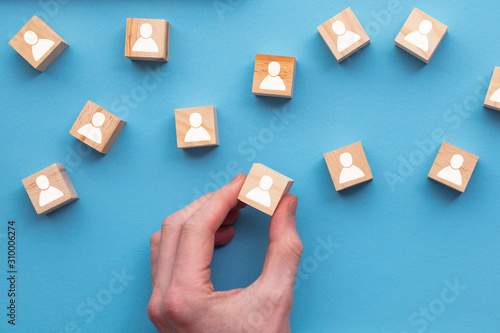 Hand choosing a wooden person block from a set. Employment choice concept