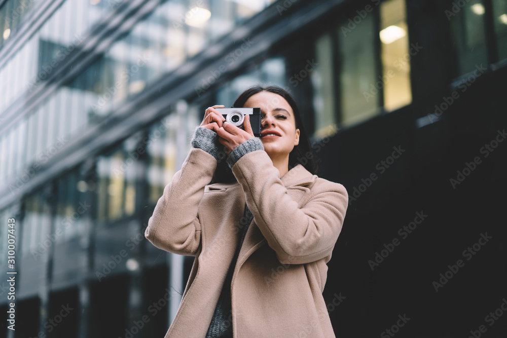 Young female in coat with eye closed taking photo on camera Young female in coat with eye closed taking photo on camera