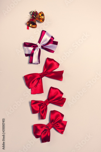 on a white background laid out four bows, and Christmas bells