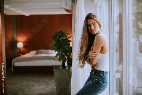 Young woman standing by the window in the room © BGStock72
