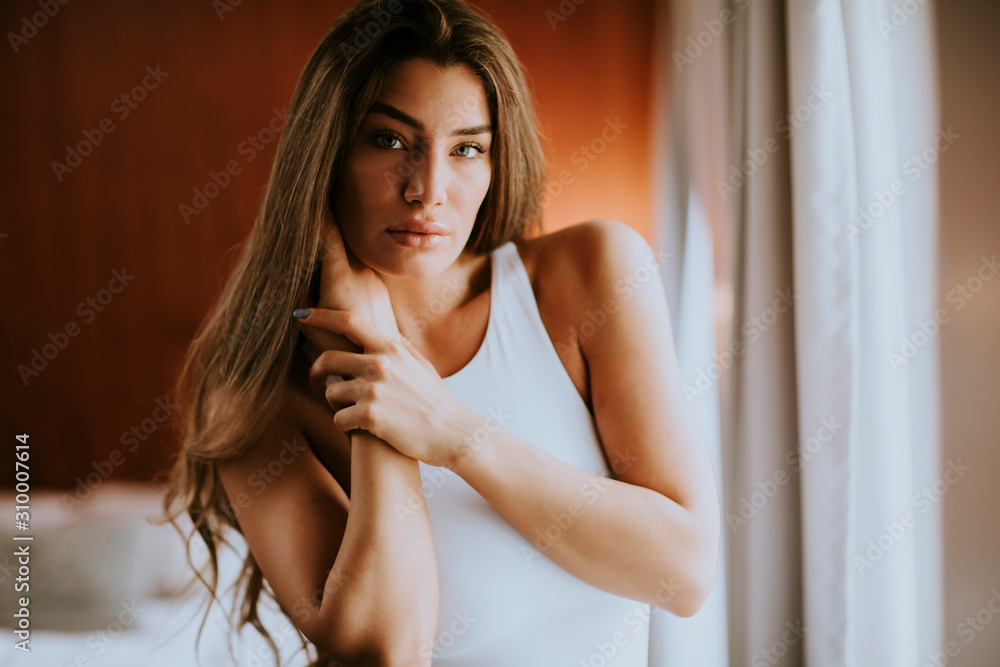 Young woman standing by the window in the room Young woman standing by the window in the room