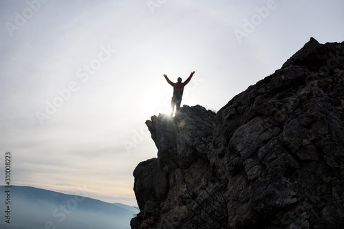 Adventurous man is standing on top of the mountain and enjoying the beautiful view. A man stands on the edge of a cliff in Sicevo Gorge, Serbia. Travel Lifestyle emotional concept