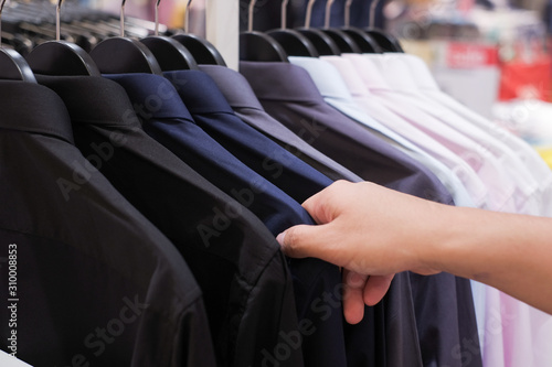 Cropped Hand Of Man choosing Men's shirts in clothing store