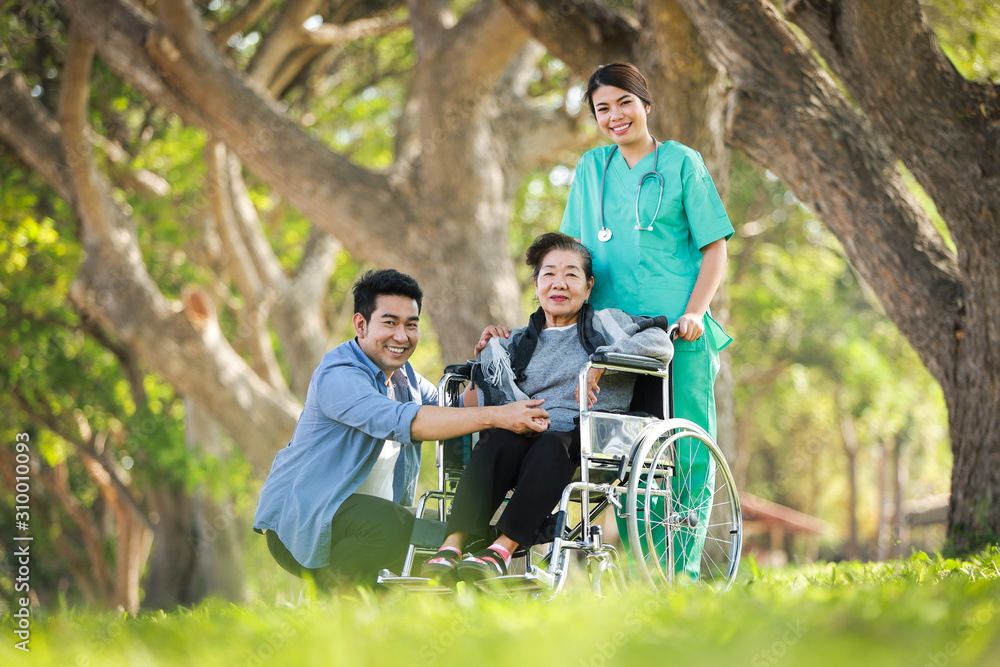 Asian senior woman sitting on the wheelchair with her son happy smile face on the green park Asian senior woman sitting on the wheelchair with her son happy smile face on the green park