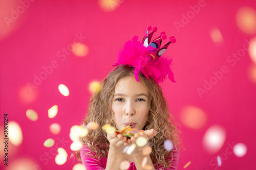 Fancy girl blowing confetti against pink bakground