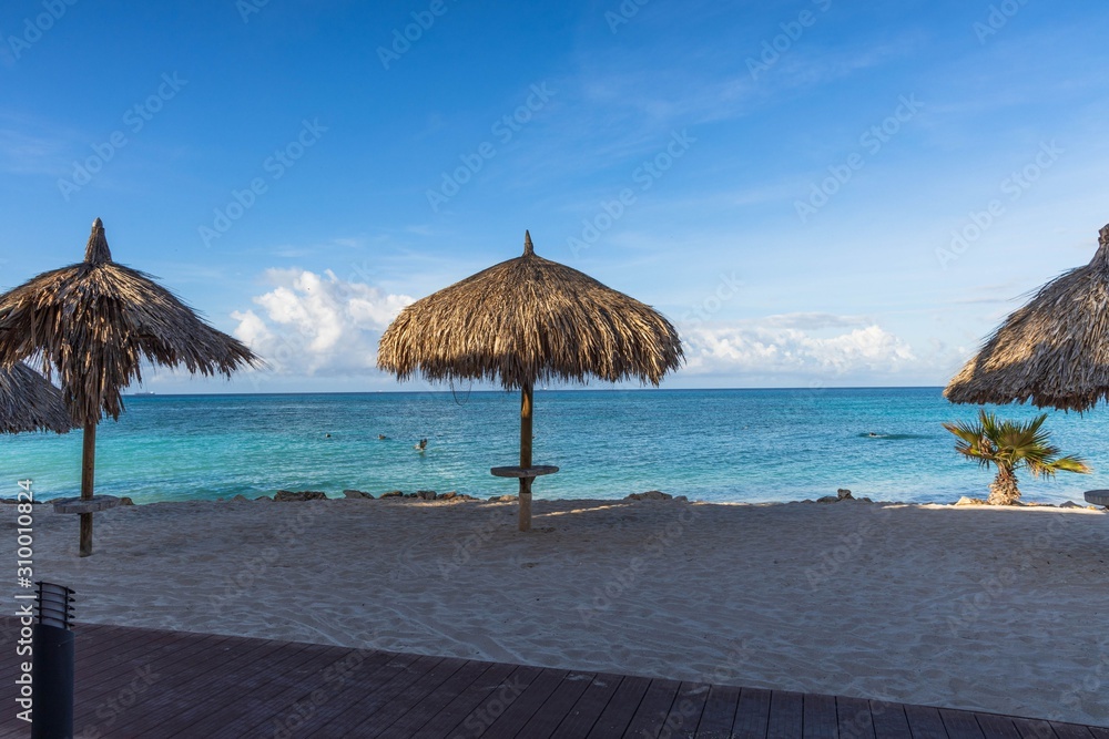 Beautiful view of white sand beach with sun umbrellas and sunbeds. Eagle beach. Aruba island. Beautiful view of white sand beach with sun umbrellas and sunbeds. Eagle beach. Aruba island.
