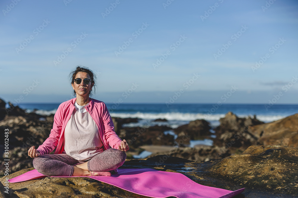 Brunette woman practicing yoga on the beach