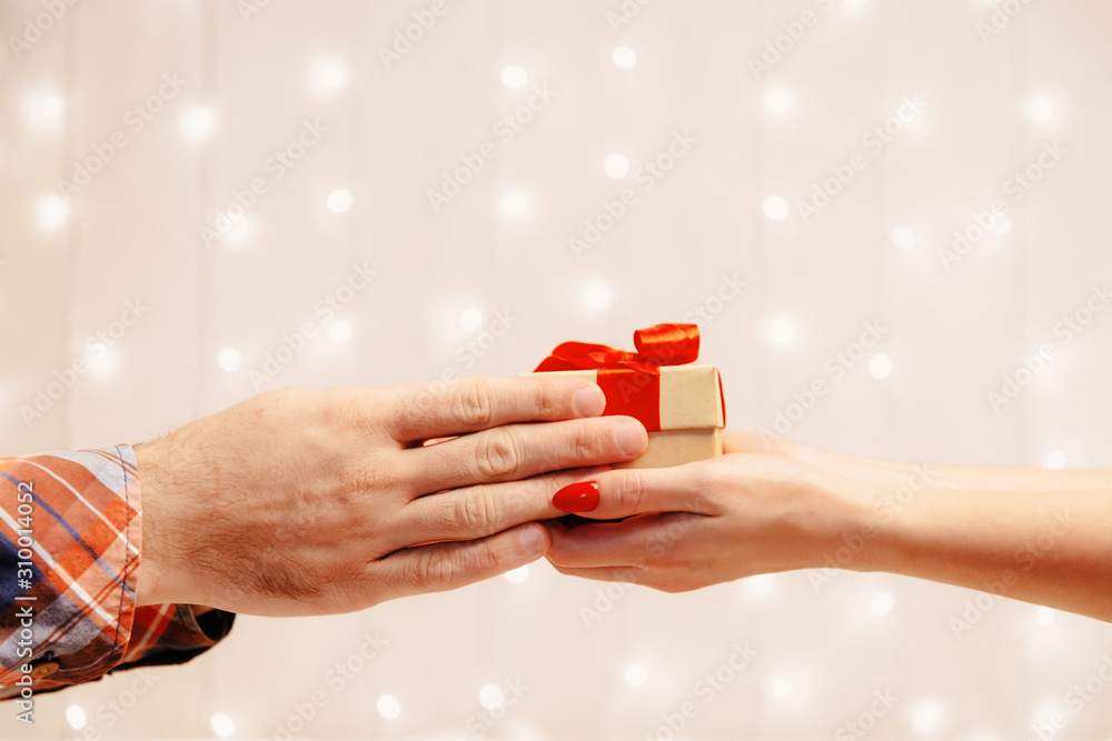 Male hands giving a gift box to woman.