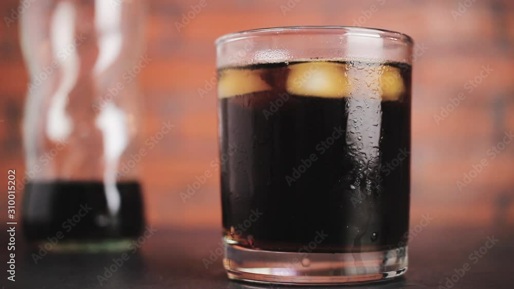 Cinemagraph, ice cubes circling in the drinking glass with carbonated soda water, close-up view on brick wall background Cinemagraph, ice cubes circling in the drinking glass with carbonated soda water, close-up view on brick wall background
