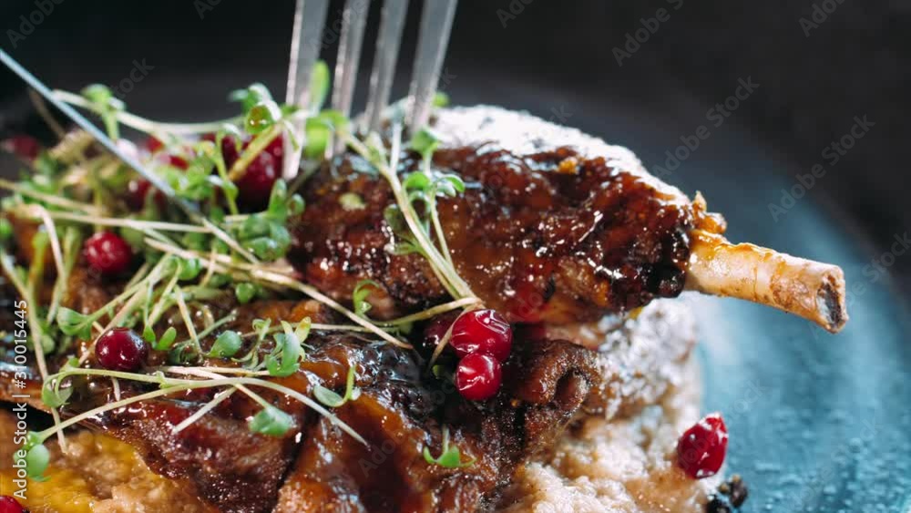 Close-up of slicing the appetizing roasted duck with fork and knife at restaurant.