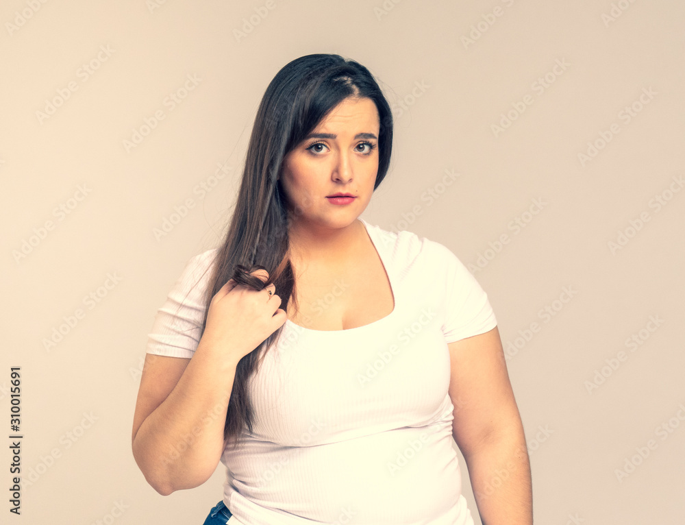 Plus Size Model with long hair twists hair on a finger Plus Size Model with long hair twists hair on a finger
