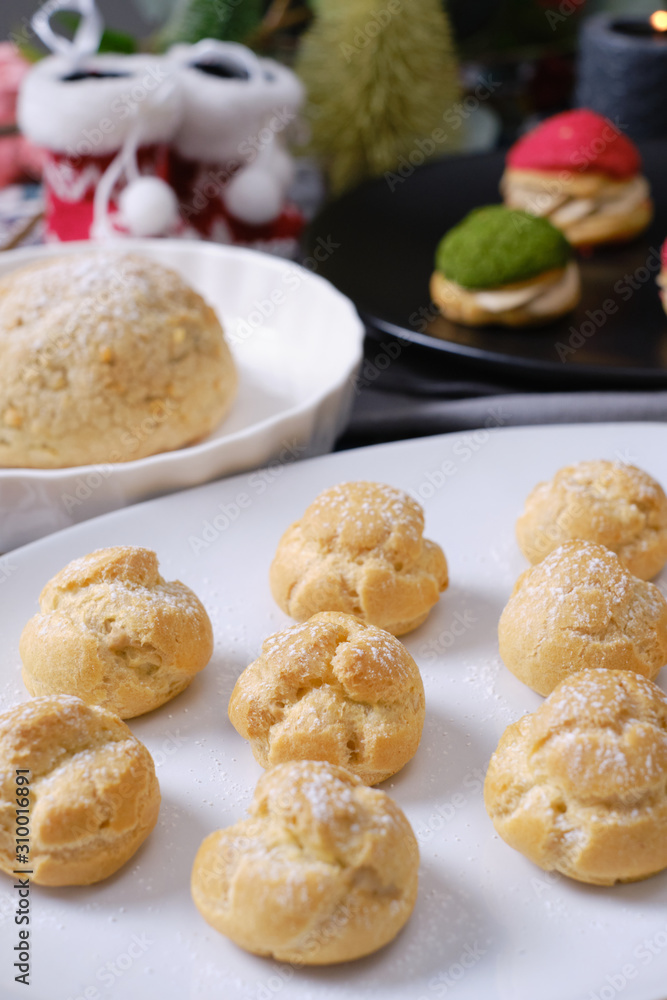 christmas choux cream or cream puff or French profiteroles with fresh cream set on cafe table.