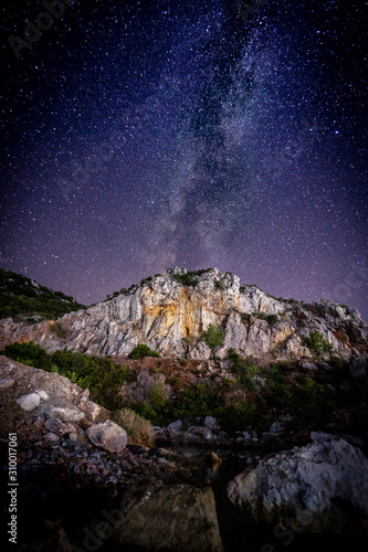 The Milky Way over the lit mountain volcano. Greece. Khalkidhiki
