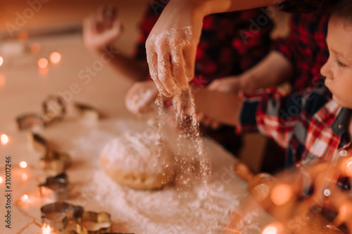 Female hand sprinkles flour on the dough for gingerbread.
