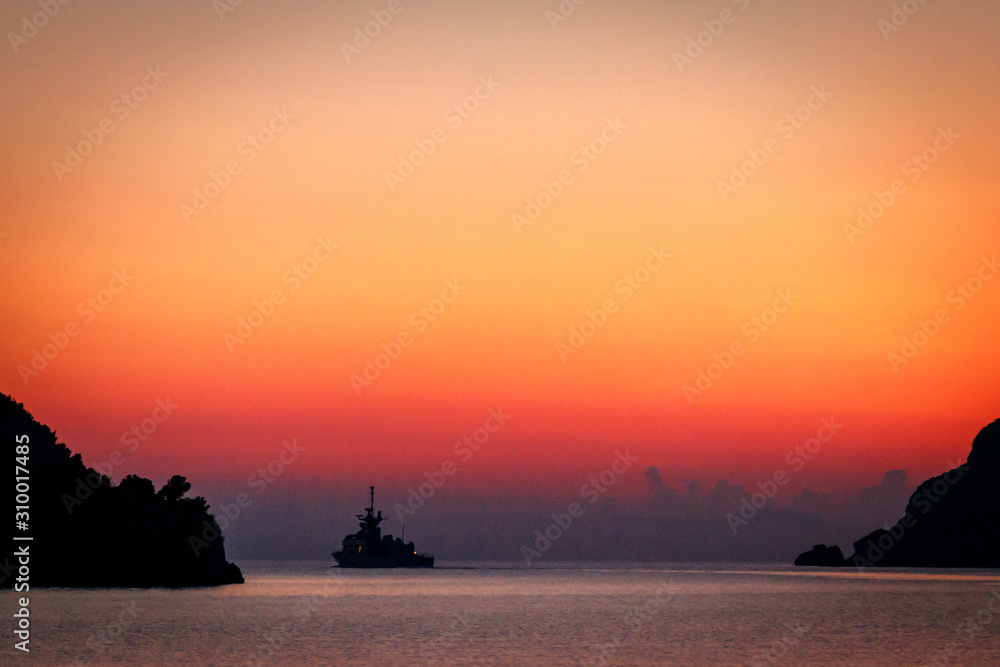 Warship against the backdrop of a red sunset sky out of the bay. Greece. Khalkidhiki