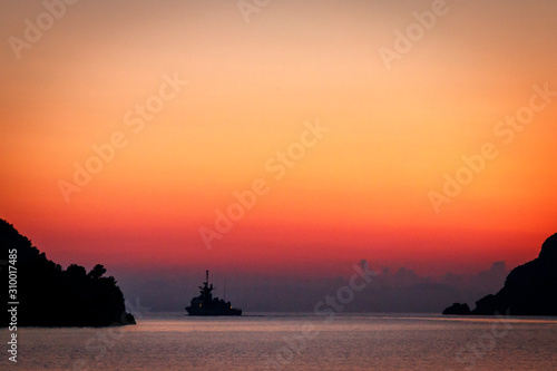 Warship against the backdrop of a red sunset sky out of the bay. Greece. Khalkidhiki © maksym