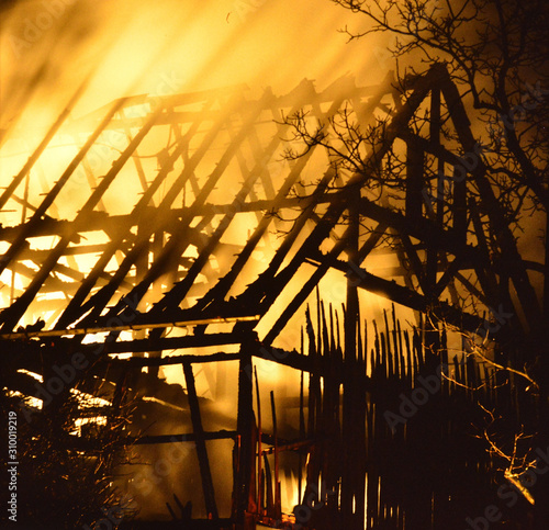 lodernde, tobende, entfachte Flammen schlagen in der Nacht aus dem Dachstuhl einer Scheune beim Brand eines Bauernhofes photo