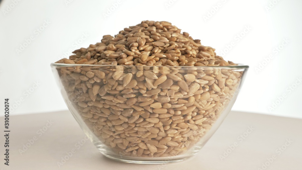 Nuts sunflower rotate are on a table in a plate. Snack in transparent dish on an isolated white background are spinning moving. Delicious and healthy protein-rich diet food. Nuts sunflower rotate are on a table in a plate. Snack in transparent dish on an isolated white background are spinning moving. Delicious and healthy protein-rich diet food.