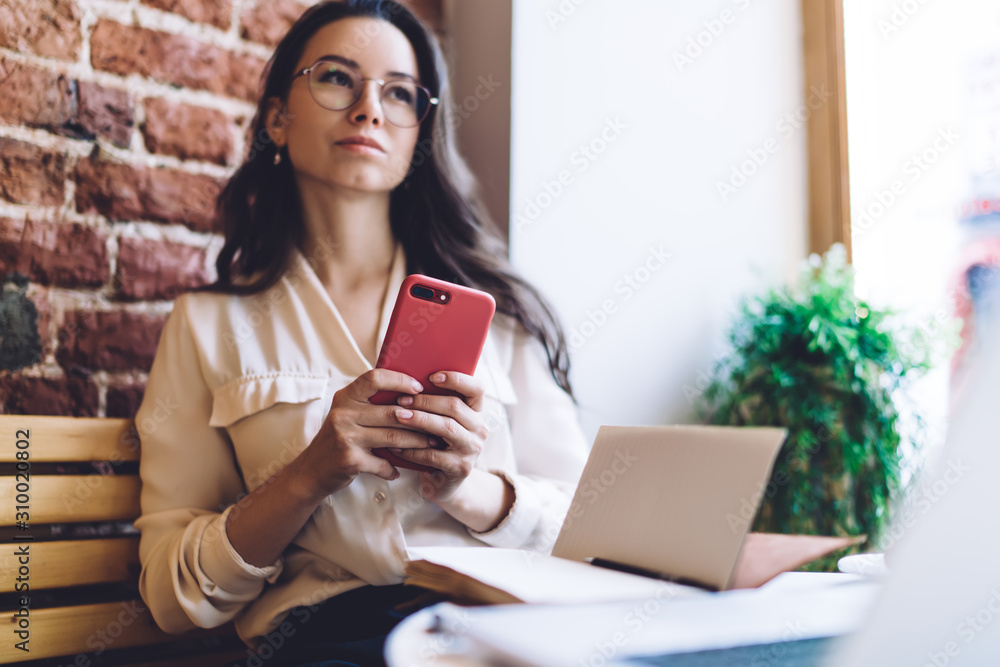 Thoughtful woman working with mobile phone and taking notes at cafe Thoughtful woman working with mobile phone and taking notes at cafe