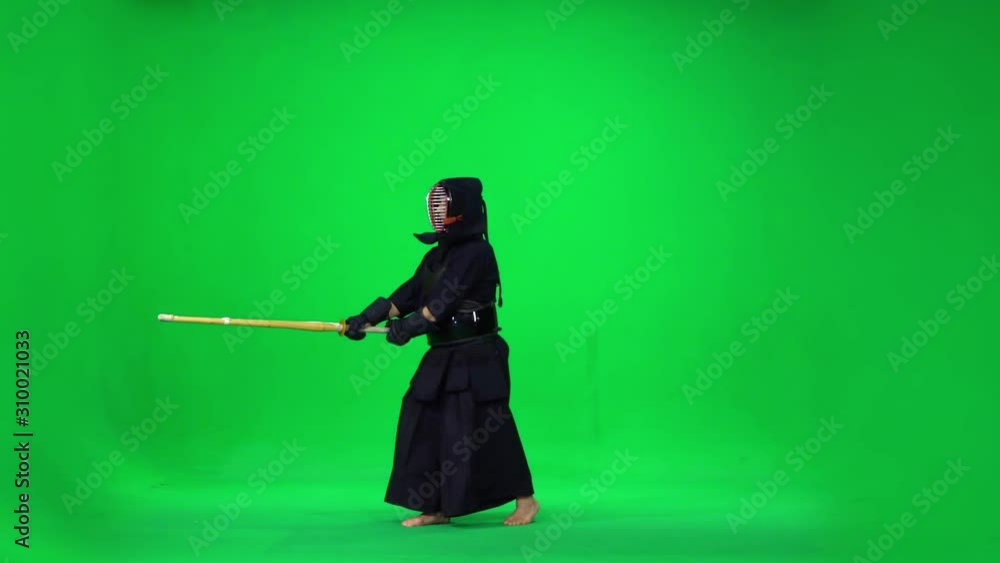Masculine Kendo warrior practicing martial art with the bamboo bokken on green screen. Slow motion Masculine Kendo warrior practicing martial art with the bamboo bokken on green screen. Slow motion