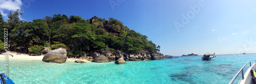Panorama, tropical beach with rocky mountain in Thailand, blue sky and greenery reflection of sea water.