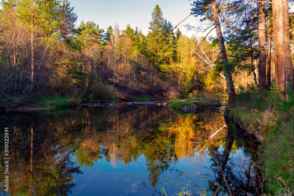 Beautiful autumn trees reflecting on the smooth water surface. Warm autumn day on the river. River bank landscape. Beautiful autumn trees reflecting on the smooth water surface. Warm autumn day on the river. River bank landscape.