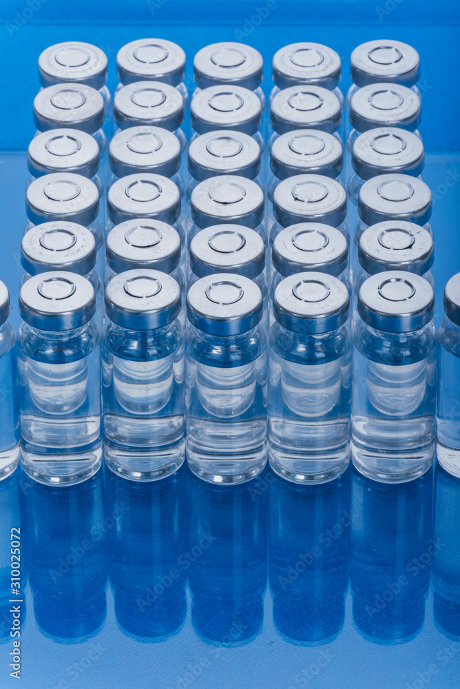 Glass medical ampoule vial for injection. Medicine is liquid sodium chloride with of aqueous solution in ampulla. Close up. Bottles ampule multicolor on background color and water. Human plasma. Glass medical ampoule vial for injection. Medicine is liquid sodium chloride with of aqueous solution in ampulla. Close up. Bottles ampule multicolor on background color and water. Human plasma.
