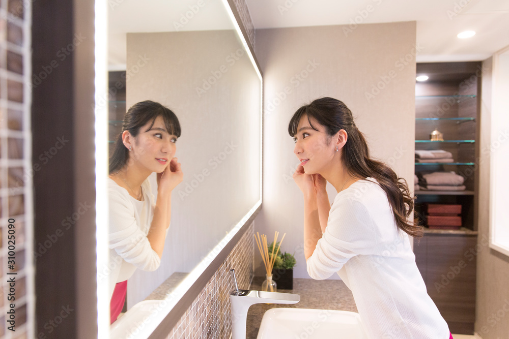 鏡の前でピアスを付ける女性 鏡の前でピアスを付ける女性