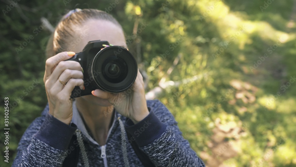 Traveler photographing scenic view in forest. One caucasian woman shooting close up look. Girl take photo video on dslr mirrorless camera. Professional photographer travel with backpack. Outdoor. Traveler photographing scenic view in forest. One caucasian woman shooting close up look. Girl take photo video on dslr mirrorless camera. Professional photographer travel with backpack. Outdoor.
