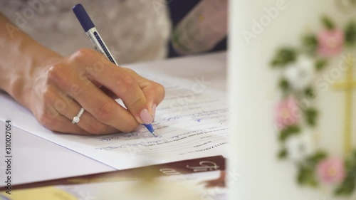bride sign wedding papers at christian wedding, candle in background, close up slow motion shot.