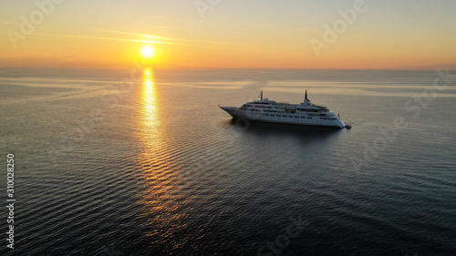 Aerial drone photo of luxury yacht docked in Aegean deep blue sea at sunset with beautiful golden colours, Greece