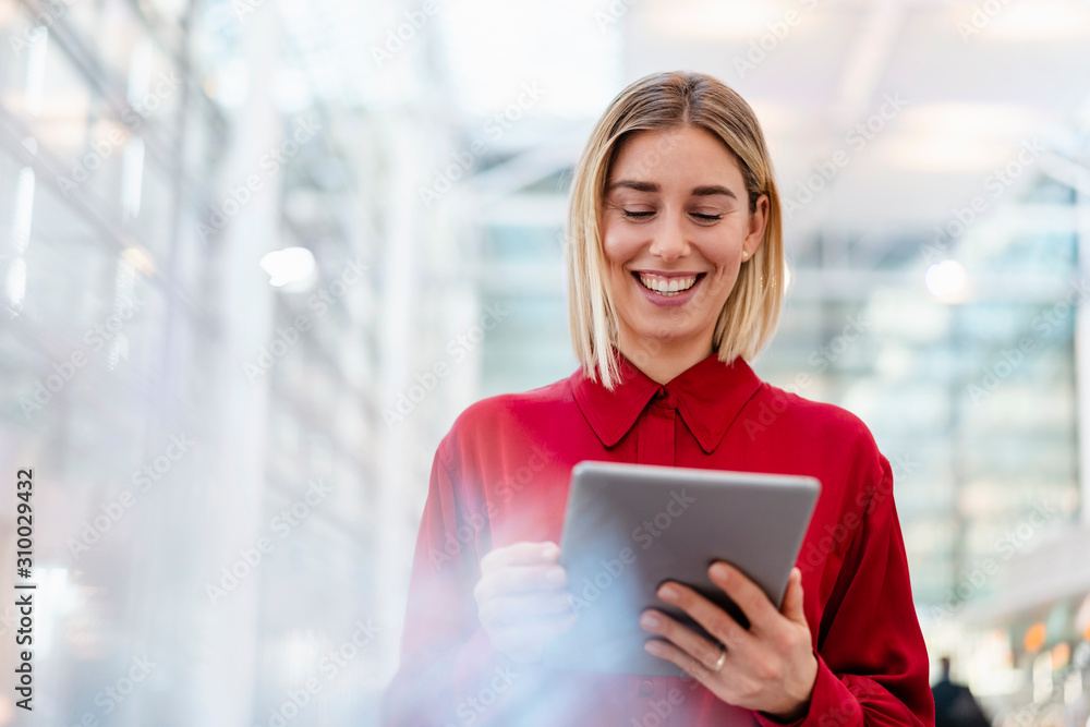 Happy young businesswoman wearing red shirt using tablet Happy young businesswoman wearing red shirt using tablet