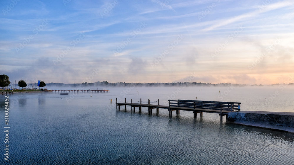 Dawn on Chiemsee Lake. In the foreground are bridges for mooring boats. Bavaria, Germany