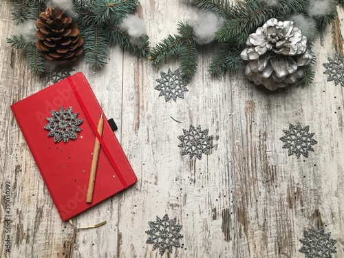 Red notenook on the wood background with new year and Christmas symbols and plants of pine tree photo