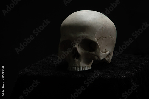 Skull lying on the altar in the dark on a black background.