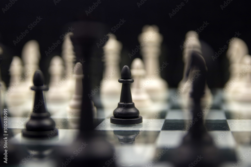 black pawn close-up on a background of white pieces on a chessboard black pawn close-up on a background of white pieces on a chessboard