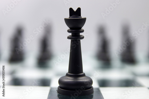 black king stands on a chessboard against the background of blurry remaining pieces