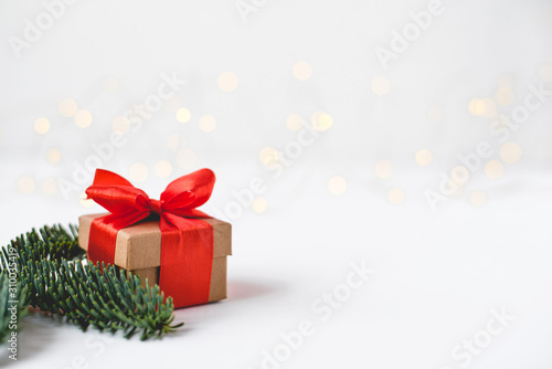 Gift box with a red bow on a background of blurred lights garland. Christmas background. © Anna
