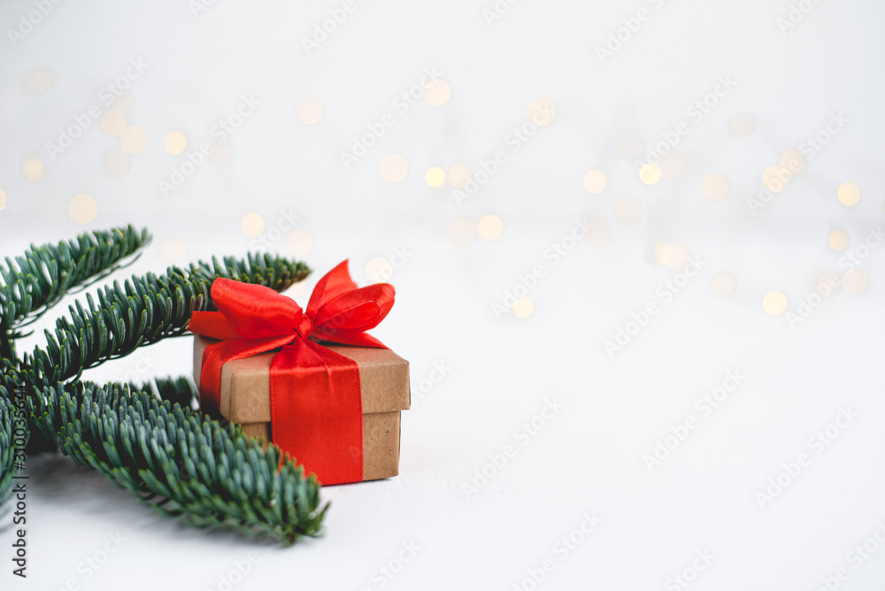 Gift box with a red bow on a background of blurred lights garland. Christmas background. Gift box with a red bow on a background of blurred lights garland. Christmas background.