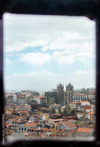 Views of the Porto Cathedral and the city buildings from a small window. Cityscape of Porto during a sunny day.
