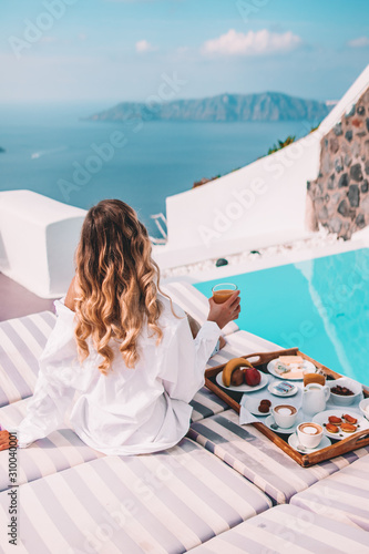 Fototapeta Naklejka Na Ścianę i Meble -  Woman having breakfast by the pool in santorini, greece