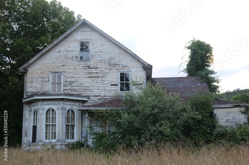 Old abandoned historic farmhouse with broken windows and peeling paint